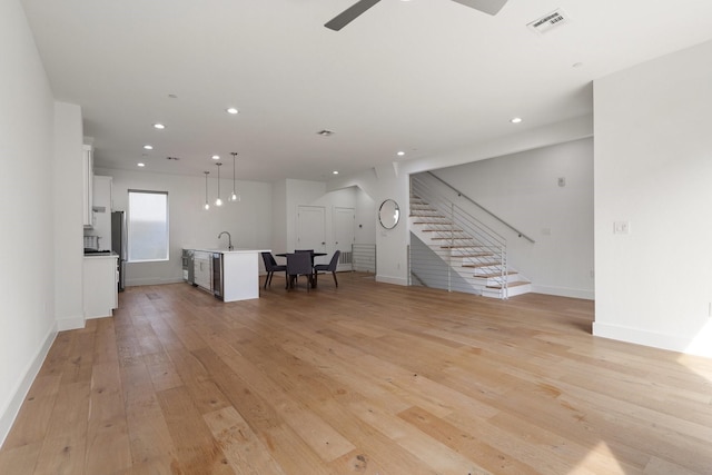 unfurnished living room with baseboards, visible vents, stairway, light wood-style floors, and recessed lighting