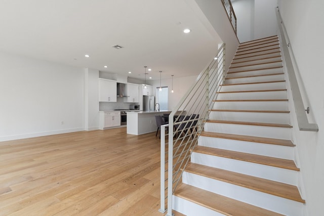 stairs with baseboards, wood finished floors, visible vents, and recessed lighting