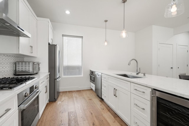 kitchen with wall chimney exhaust hood, wine cooler, stainless steel appliances, white cabinetry, and a sink