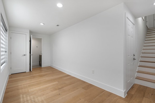 spare room with visible vents, baseboards, stairs, light wood-type flooring, and recessed lighting