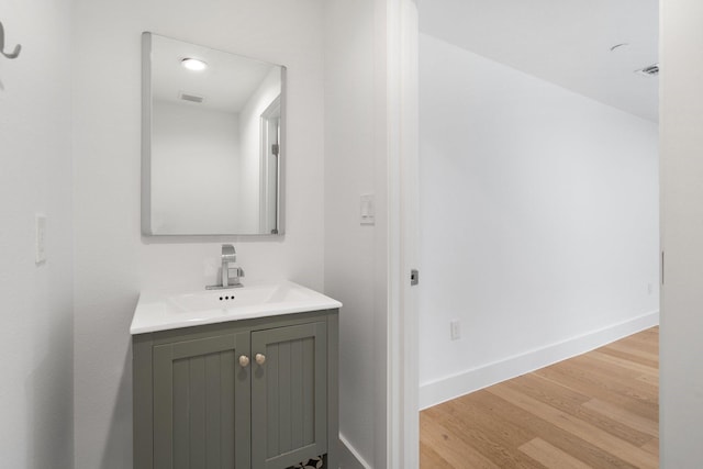 bathroom with visible vents, wood finished floors, vanity, and baseboards