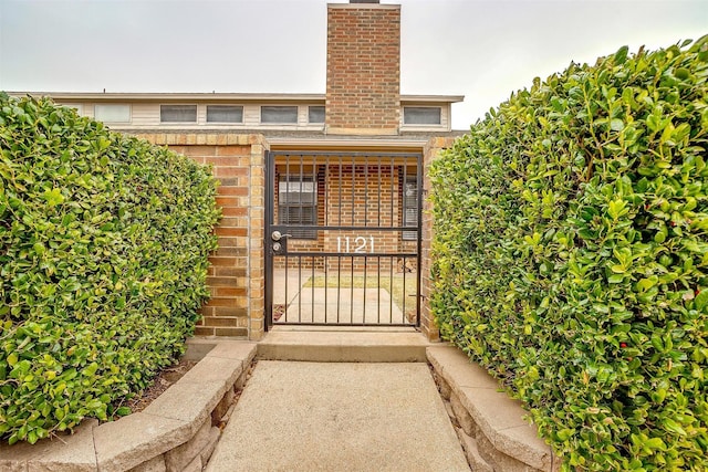 view of exterior entry with a chimney and brick siding