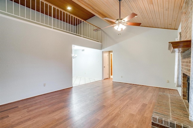 unfurnished living room with a fireplace, ceiling fan, wood finished floors, high vaulted ceiling, and wooden ceiling