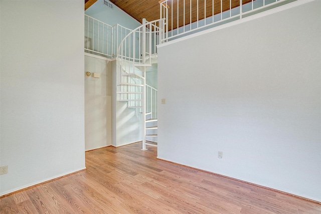 empty room with stairs, a high ceiling, and wood finished floors