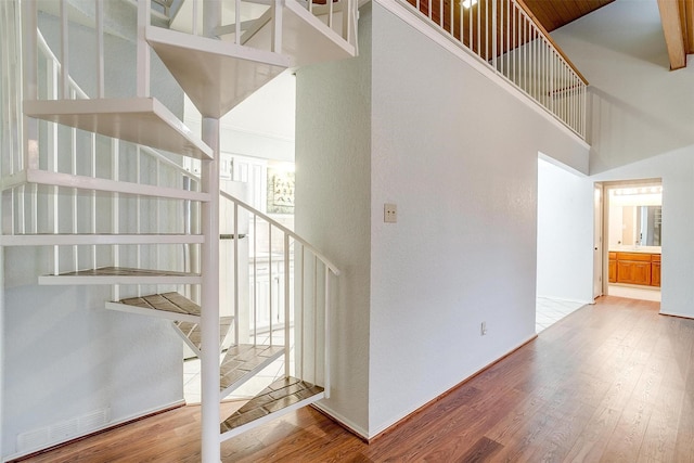 stairway with wood-type flooring and a high ceiling