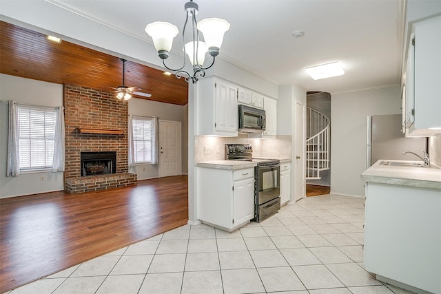 kitchen featuring light tile patterned floors, black appliances, a sink, and light countertops