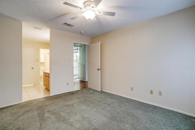 unfurnished bedroom with a textured ceiling, visible vents, and light colored carpet