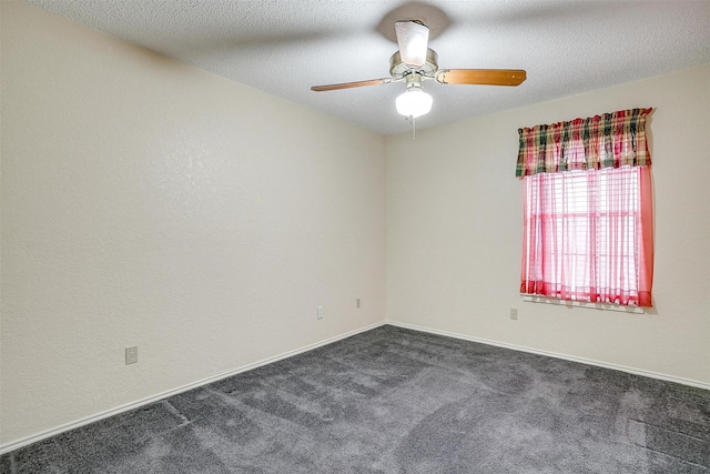 empty room featuring a ceiling fan, baseboards, dark colored carpet, and a textured ceiling