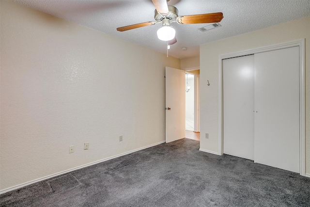 unfurnished bedroom with a textured ceiling, ceiling fan, dark carpet, and visible vents