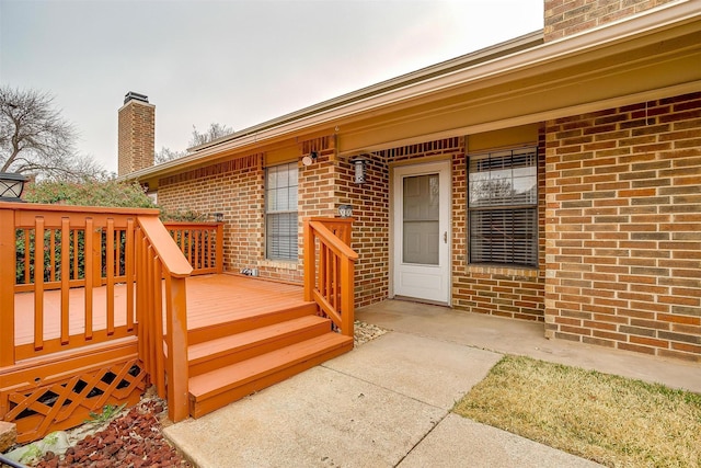 property entrance featuring a chimney and brick siding