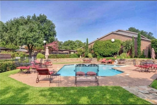 pool featuring a patio area, fence, and a lawn