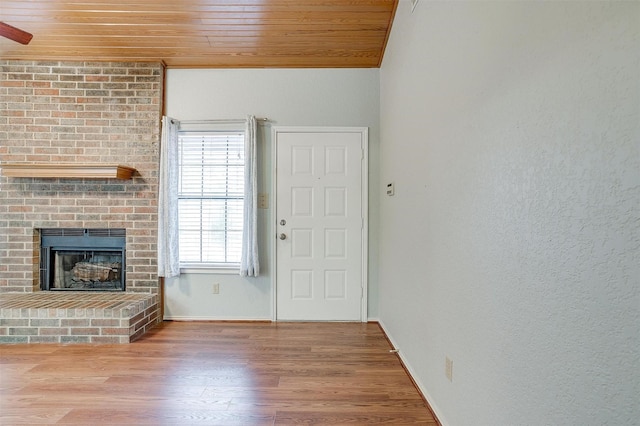 unfurnished living room featuring a brick fireplace, wood finished floors, wooden ceiling, and baseboards