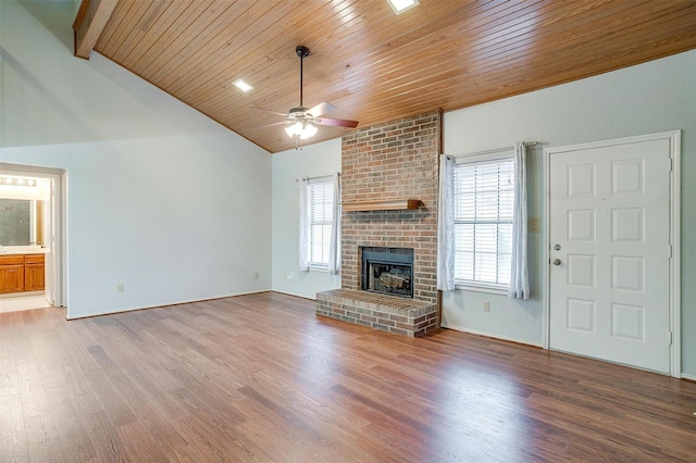 unfurnished living room featuring lofted ceiling with beams, a ceiling fan, a brick fireplace, wood finished floors, and wooden ceiling