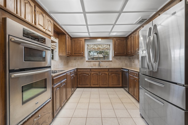 kitchen featuring light tile patterned floors, decorative backsplash, stainless steel appliances, light countertops, and a sink