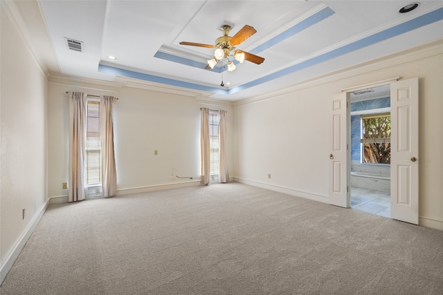 empty room with visible vents, a ceiling fan, ornamental molding, carpet, and a raised ceiling