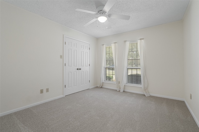 unfurnished room featuring ceiling fan, a textured ceiling, baseboards, and carpet flooring