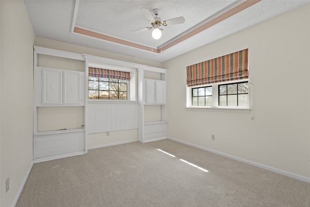 spare room with a ceiling fan, light colored carpet, plenty of natural light, and a textured ceiling