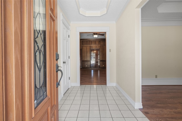 foyer entrance featuring a textured ceiling, light tile patterned floors, ornamental molding, and baseboards