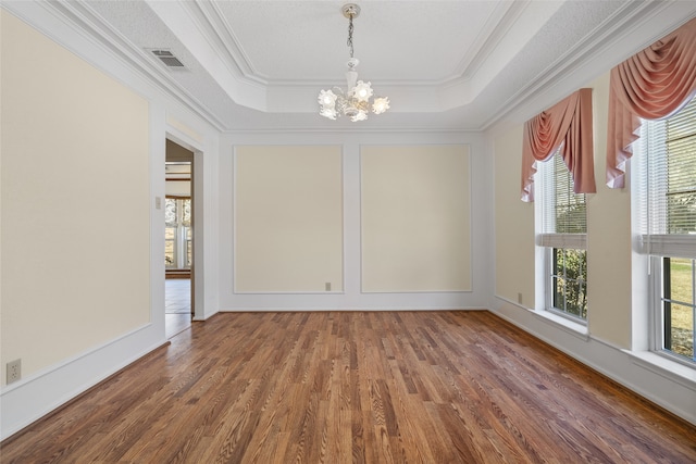 spare room with a chandelier, a tray ceiling, and plenty of natural light