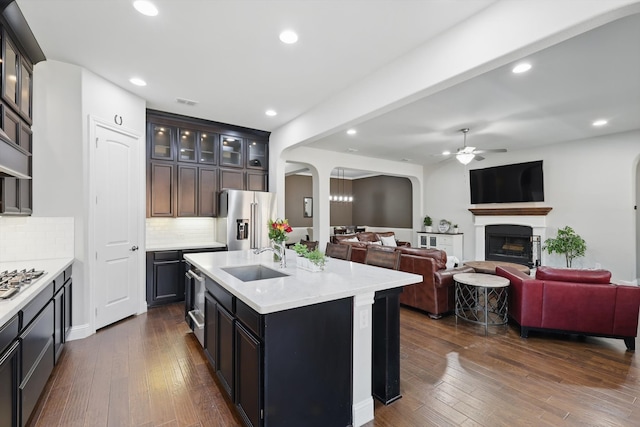 kitchen with ceiling fan, dark wood finished floors, appliances with stainless steel finishes, arched walkways, and a sink