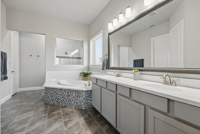 full bathroom featuring a garden tub, double vanity, visible vents, and a sink