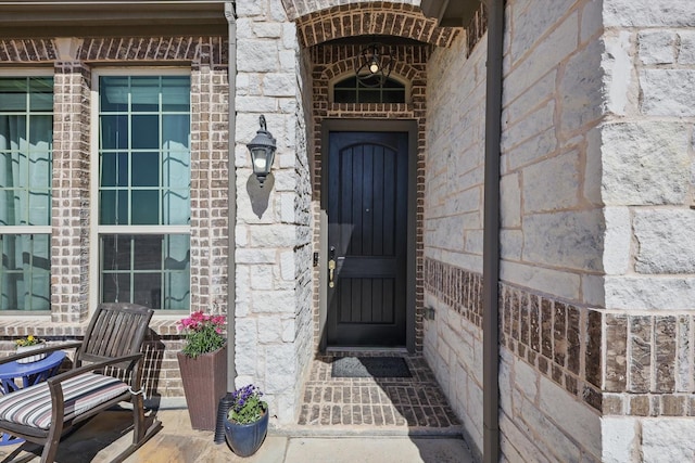 entrance to property featuring brick siding and stone siding