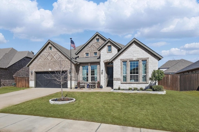 french country inspired facade featuring stone siding, driveway, a front yard, and fence