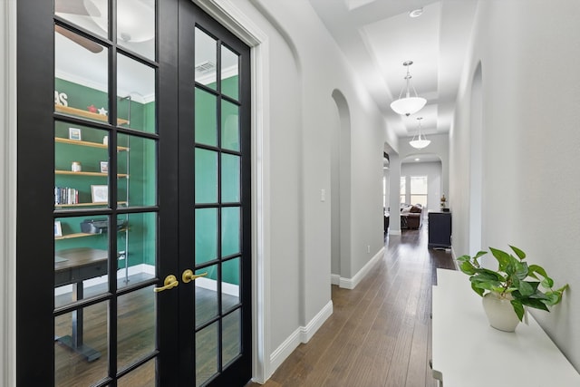 corridor with arched walkways, french doors, baseboards, and dark wood-style flooring