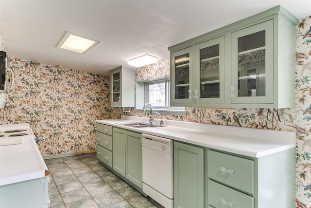 kitchen with green cabinetry, white dishwasher, a sink, and wallpapered walls