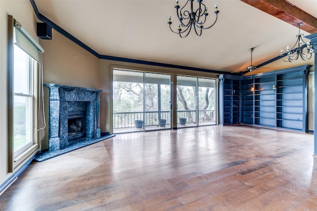 unfurnished living room with a chandelier, a high end fireplace, lofted ceiling with beams, and hardwood / wood-style flooring