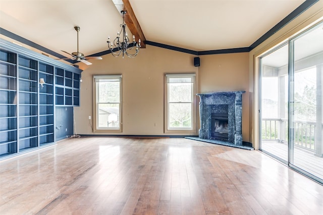 unfurnished living room with lofted ceiling with beams, wood finished floors, a high end fireplace, and a healthy amount of sunlight