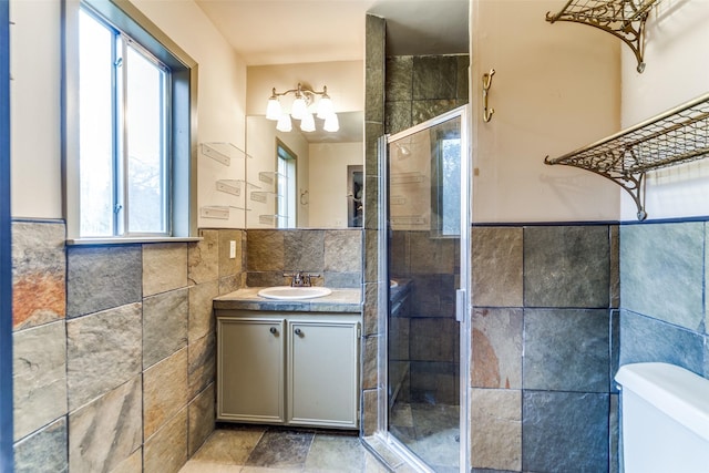 full bathroom with a wainscoted wall, tile walls, toilet, a stall shower, and vanity