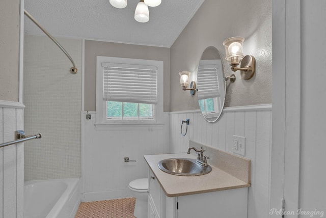 bathroom featuring a textured ceiling, toilet, a wainscoted wall, vanity, and shower / washtub combination