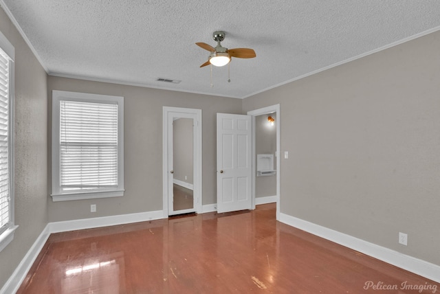 interior space featuring ornamental molding, wood finished floors, visible vents, and baseboards