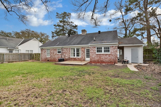 rear view of house with brick siding, a lawn, a chimney, and a fenced backyard