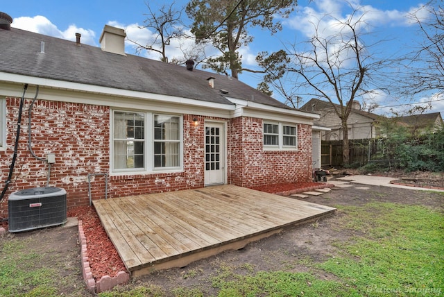 rear view of property featuring central air condition unit, a chimney, a deck, and brick siding