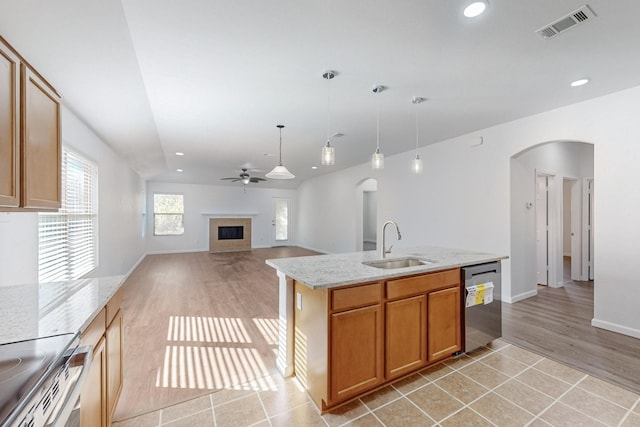 kitchen with arched walkways, visible vents, stainless steel appliances, a fireplace, and a sink