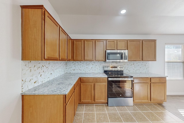 kitchen featuring light stone counters, brown cabinets, light tile patterned floors, stainless steel appliances, and backsplash