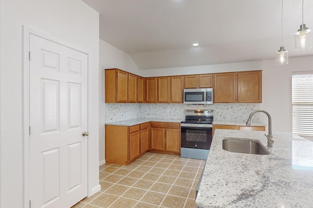 kitchen featuring light tile patterned floors, stainless steel appliances, hanging light fixtures, brown cabinetry, and a sink