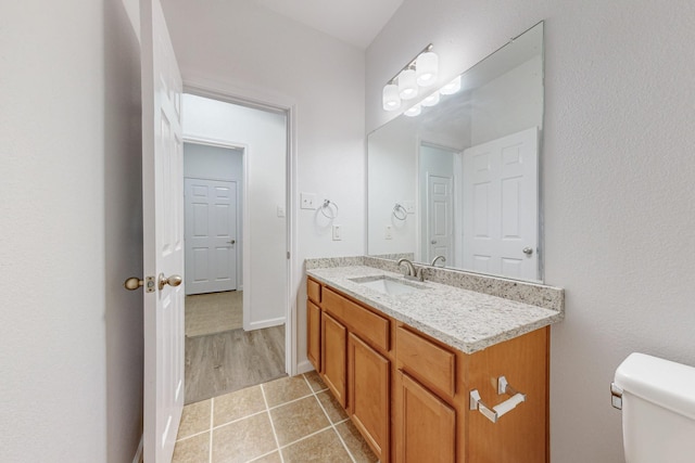 bathroom with toilet, tile patterned flooring, baseboards, and vanity