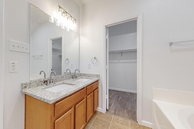 bathroom with double vanity, a walk in closet, and a sink