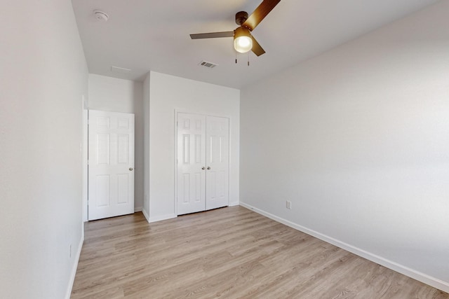 unfurnished bedroom featuring light wood finished floors, baseboards, visible vents, and a closet