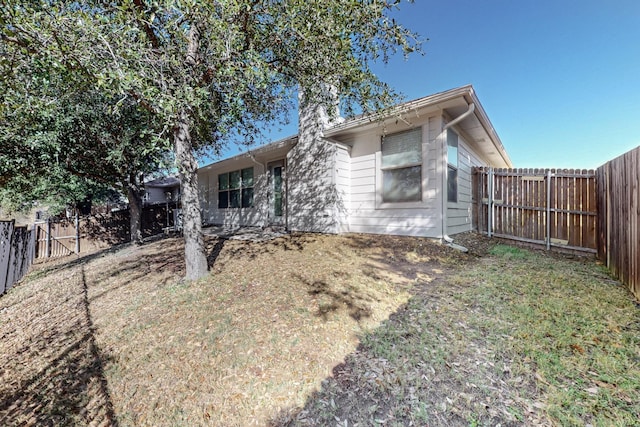 view of front of house featuring a fenced backyard, a chimney, and a front lawn