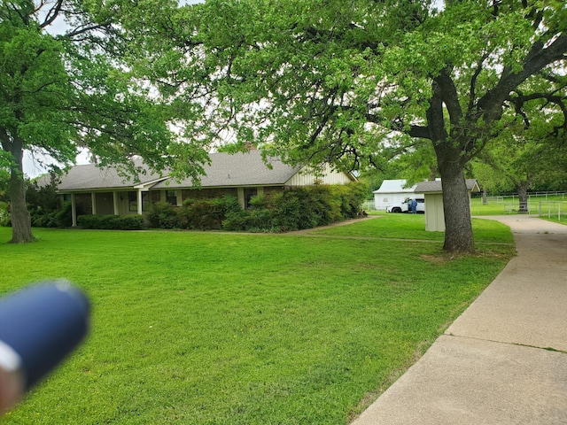 view of front facade featuring a chimney, roof with shingles, a front yard, and fence