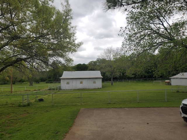 view of yard with an outbuilding, a rural view, an outdoor structure, and fence