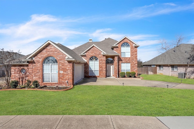 traditional-style home featuring brick siding, a chimney, an attached garage, a front yard, and driveway