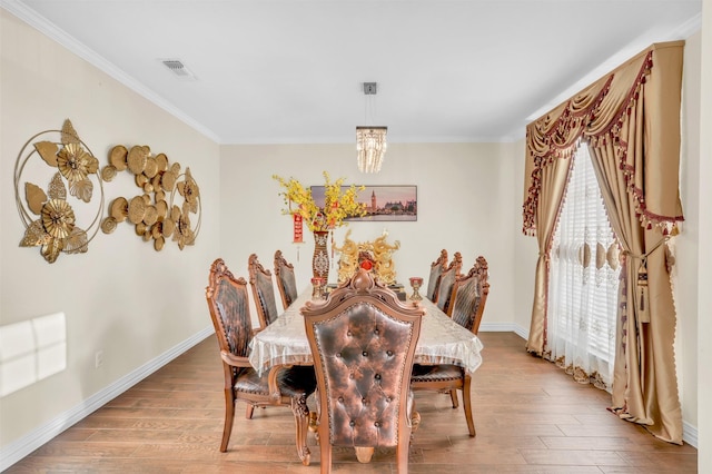 dining room featuring visible vents, crown molding, baseboards, and wood finished floors