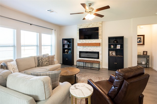 living area featuring a ceiling fan, visible vents, a fireplace, and wood finished floors