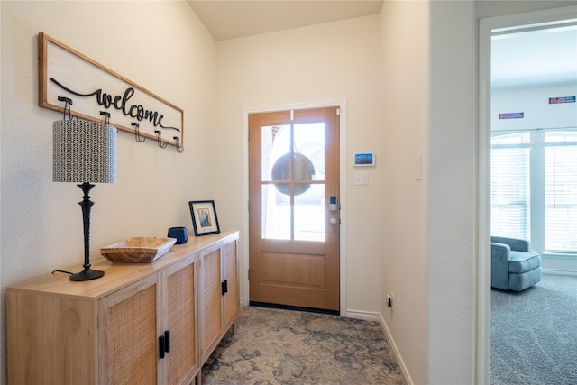 doorway featuring carpet and baseboards