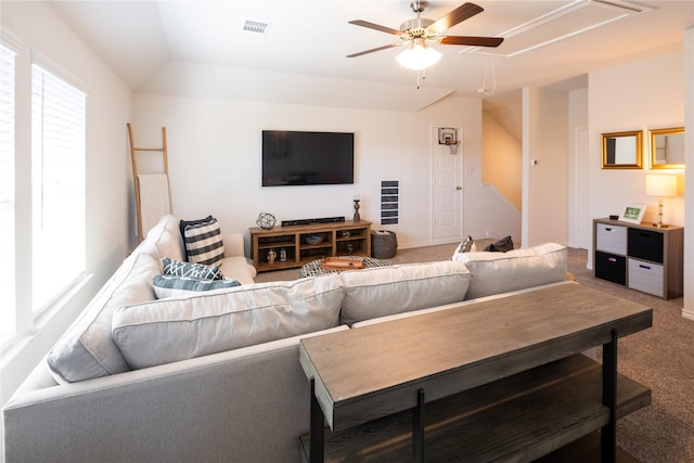 carpeted living area with ceiling fan, attic access, visible vents, and vaulted ceiling